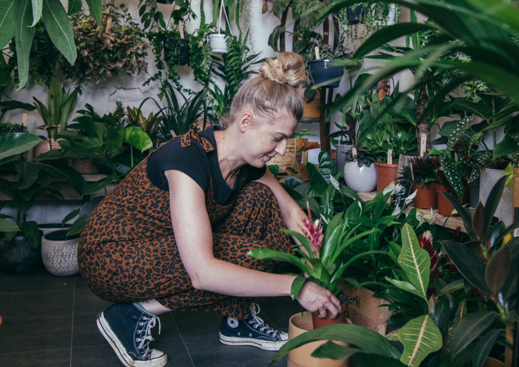 Lady bending over to adjust a plant in a houseplants shop.